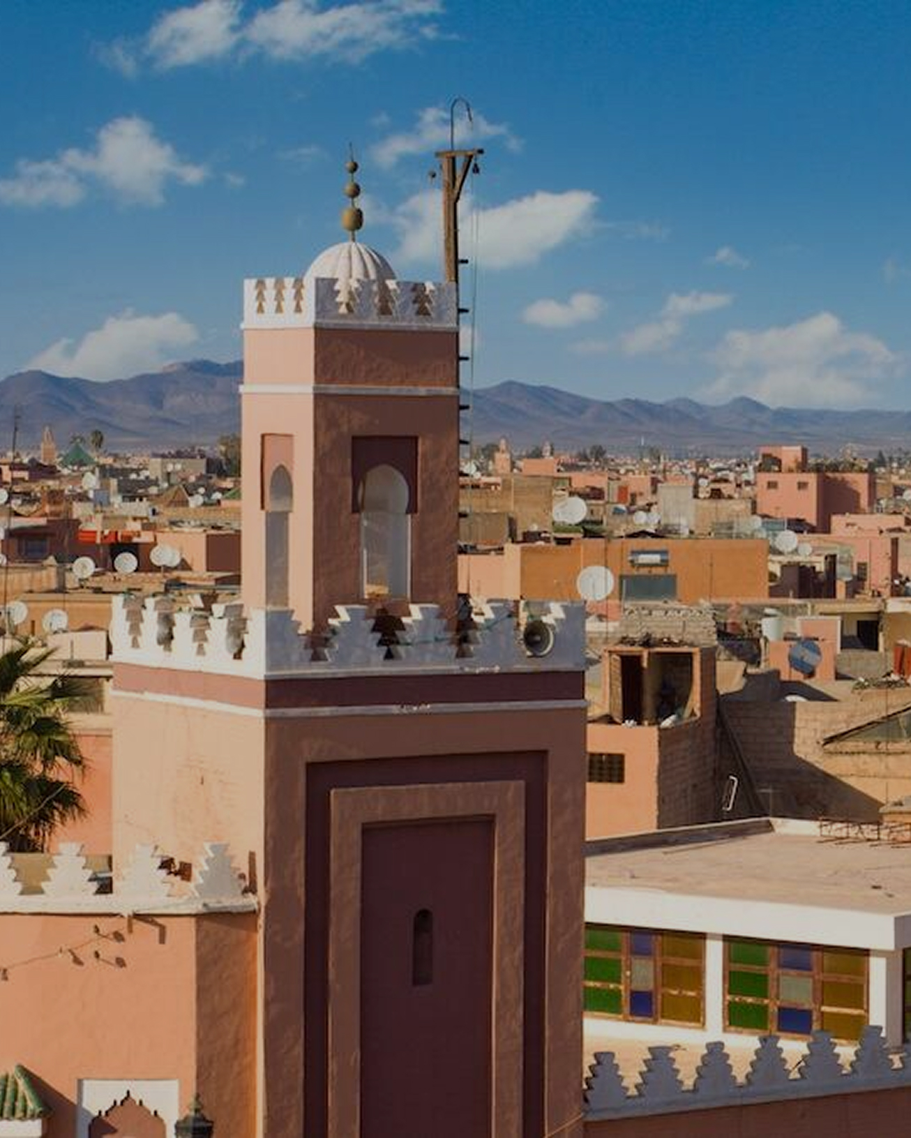 A sunlit minaret above the rooftops in the middle of the day